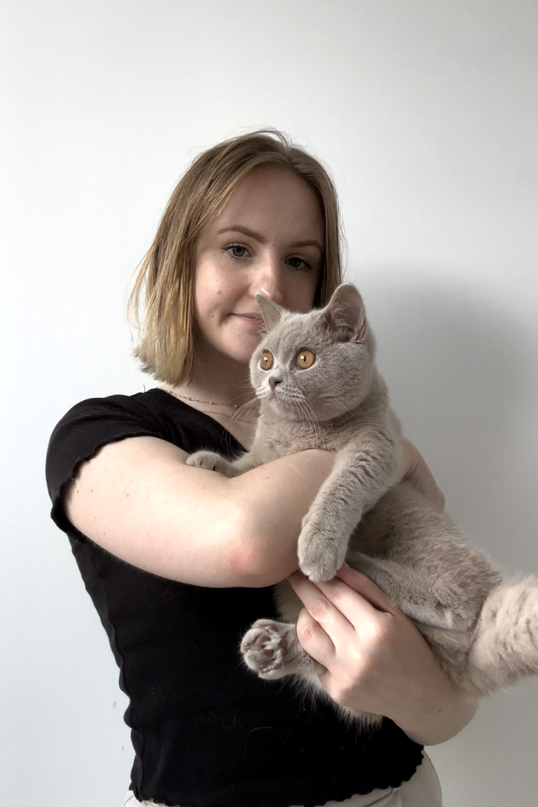 Alina hält ihre graue Katze "Luna" mit orangefarbenen Augen in ihren Armen.